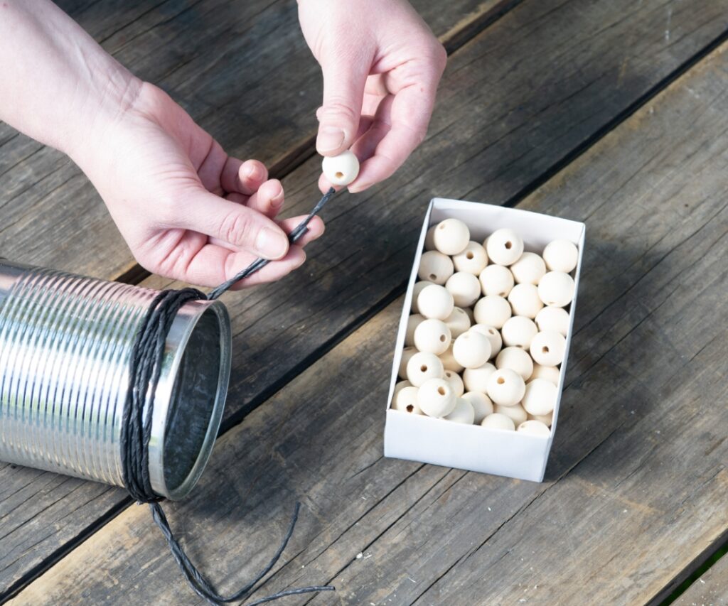 Materialien für ein DIY Insektenhotel aus einer Konservendose, um einen geschützten Nistplatz für Wildbienen in der Nähe von Geranien zu schaffen.