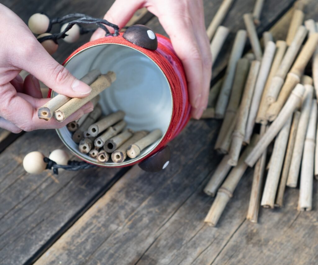 Die Dose wird mit hohlen Stängeln befüllt, die Wildbienen als Niströhren dienen, ideal platziert neben nektarreichen Geranien.